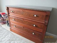 Front view showing three drawers, burl panels, brass and ceramic pulls