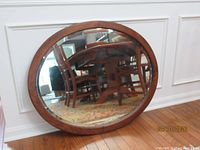 Front view of oak framed oval mirror leaning against wall