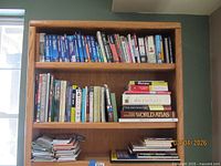Bookshelf with three shelves of travel and reference books, maps stacked on bottom