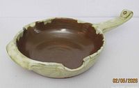 Oblique view of terracotta earthenware pan showing interior, glaze, handle and pour spout