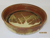 Top angled view of brown glazed stoneware bowl showing interior abstract cream design