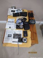Overview of all three cameras, accessories, manuals, DVDs and two binoculars laid out on table