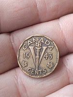 Reverse of 1943 Canadian 5-cent coin showing torch, V and maple leaves