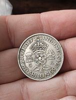 Reverse of 1947 one shilling coin showing crowned Tudor rose, thistle and shamrock, date and denomination