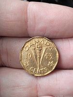 Reverse of 1943 Canadian 5-cent coin showing torch, V, maple leaves and date