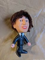 Front view of John Lennon plastic figure in black suit