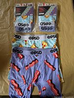 Two sealed two-packs plus four loose boxer briefs showing bacon and pizza prints