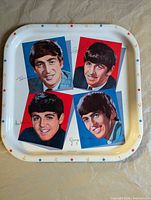 Front of white metal tray showing four Beatles portraits, stars and musical note border