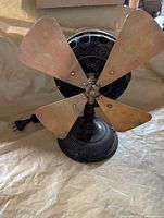 Front view of cast-iron fan showing four brass blades and ribbed base