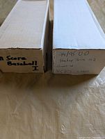 Two long cardboard boxes, one labeled 94/95 U.D Hockey Series 1+2, the other labeled 91 Score Baseball I