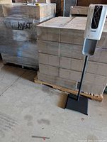 Full view of freestanding Ecolab soap dispenser on black metal stand next to pallet for scale