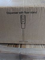Carton printed with 'Dispenser with floor stand' line drawing
