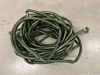 Coiled green garden hose showing overall appearance and shut-off valve end