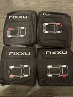 Four folded black Rixxu seat covers with car graphic visible