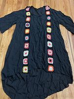 Full view of black cardigan laid flat
