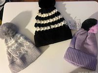 Three knit pom beanies laid out