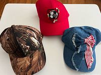 Front view of three baseball caps showing colours and decorative details