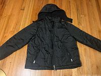 Front view of black youth XL puffer jacket with hood and zip pockets