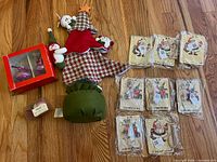 Group shot showing all new Christmas items: wall hanging, plush figures, felt basket, boxed ornaments, boxed soap/candle, sealed gift tag packs