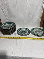 Stack of 12 bowls beside 3 plates on white backdrop