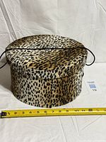Leopard print round hat box with lid closed, tape measure shows ~13 in diameter