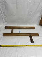 pair of tonfa laid parallel on white backdrop with tape measure for scale
