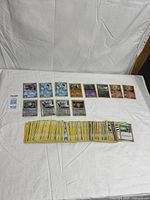 Overall view showing stack of roughly 100 yellow-border Pokémon cards and top row of notable rares/foils