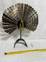 Front view of entire metal peacock sculpture showing tail and base
