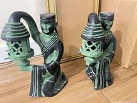 Both bronze patinated figurine candle holders side by side on floor
