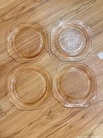 All four pink glass dinner plates on floor showing overall pattern and shape