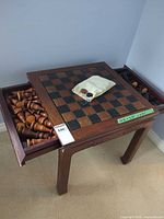 Full view of chess table with both drawers open showing brown and black chess pieces, small cloth bag on board