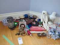 Overall group of items laid out: plush rabbit, lantern, candles, coin sorter, cassette tin, faux flowers, ribbons, figurines, framed art
