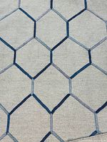 Close view of rug showing blue hexagon lattice on cream background