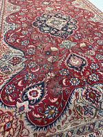 Angled close shot of rug illustrating wear, central medallion and floral details