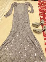 Full view of gray/silver lace gown laid flat with matching glitter heels