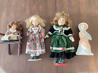 Group shot of four dolls with chair and stands