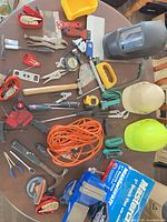 All items laid out on table including bench vise, welding helmet, hard hats, extension cord and assorted tools