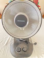 Front view of NOMA oscillating space heater showing grille, control panel, power cord