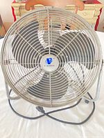 Front view of Powermax metal floor fan showing grille, blades, and stand