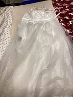 Full view of white lace and tulle wedding dress laid flat on table