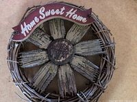 Front view of grapevine wreath with wooden flower and red Home Sweet Home sign