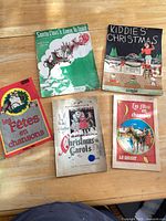 Front covers of five Christmas songbooks laid on table