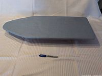 Top view of ironing board showing blue fabric surface and overall shape with marker for scale