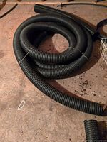 Two coiled lengths of black corrugated pipe on floor