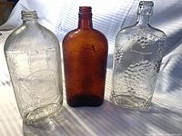 Front view of three vintage bottles showing colors and embossing
