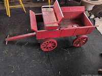 Full view of red wooden pull wagon showing body, seat, wheels and broken handle