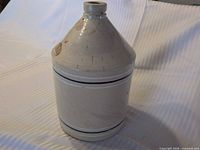 full view of beige stoneware jug showing blue bands and overall shape