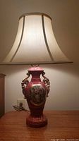 Full view of burgundy porcelain Victorian style table lamp with shade