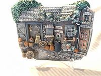 Front view of stoneware wall plaque showing detailed farm produce and cottage scene
