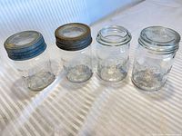 Front view of four jars showing embossing and two lids